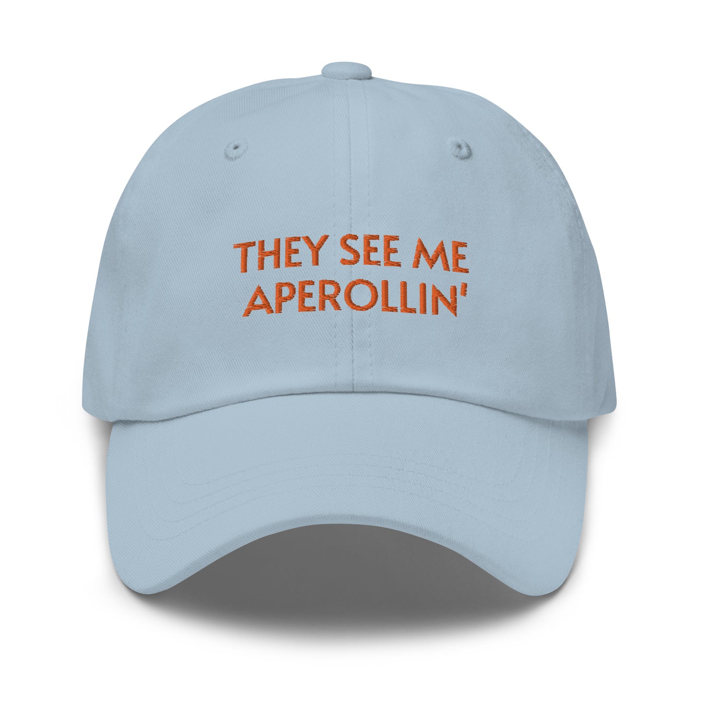 Bild eines Baseball-Caps mit der Bestickung 'They see me Aperolin'' auf weißem Hintergrund. Ein lustiges Accessoire für Aperol-Liebhaber aus 100% Baumwoll-Chino-Cord.