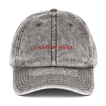 Produktbild einer Vintage-Cap mit dem Spruch 'I HATE IT HERE' auf einem weißen Hintergrund. Das perfekte Accessoire für Partymuffel.